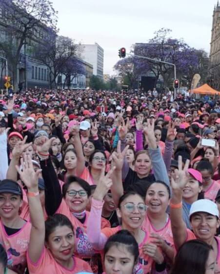 Multitud de participantes en la Carrera Bonafont reunidos en el centro histórico, vistiendo playeras rosas y celebrando antes de la carrera